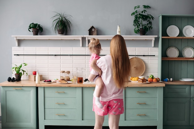 Mother having breakfast with her lovely daughter in the kitchen