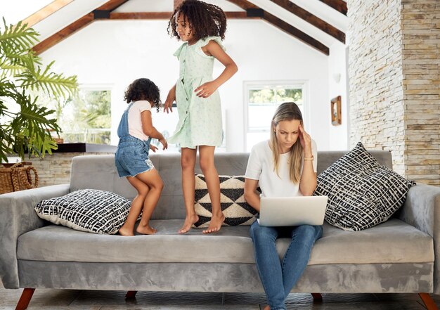 Mother headache and work from home on laptop kids or jump on sofa in living room comic game or fun Mom girl siblings and computer with stress burnout or tired with freelance job in family house