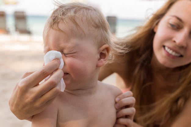 Mother helping baby to blow nose