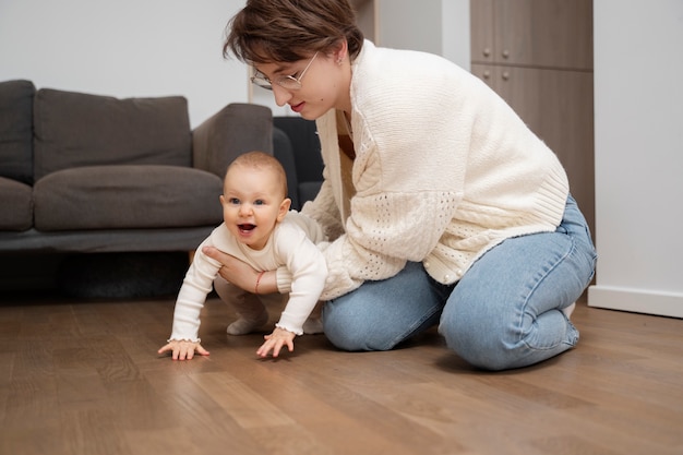 Photo mother helping baby crawl full shot