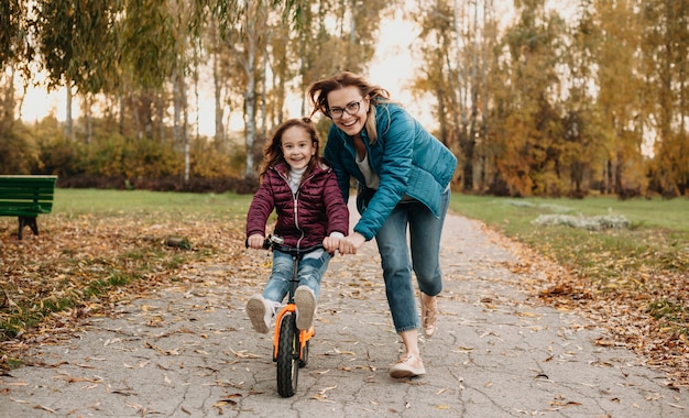 mother helping her daughter to ride a bike