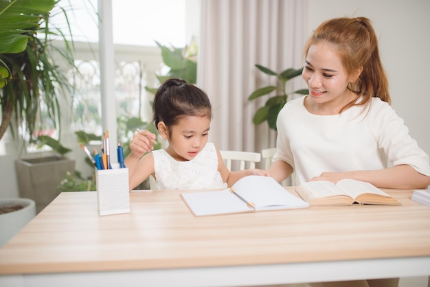 Photo mother helping her little child with homework