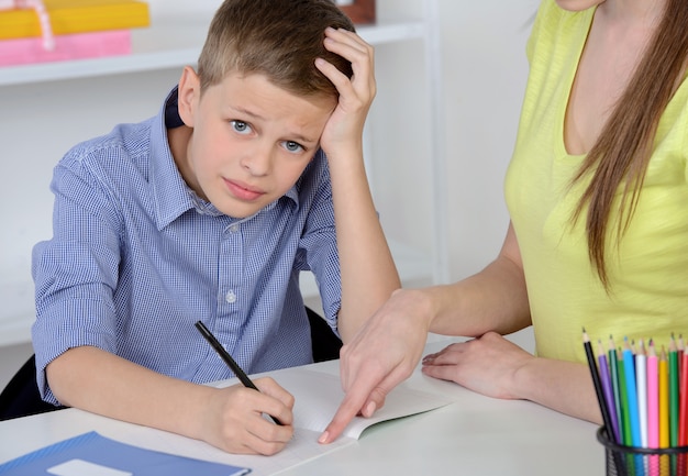 Mother helping to her son doing homework at home.