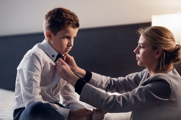 Foto una madre che aiuta il figlio a prepararsi per la scuola