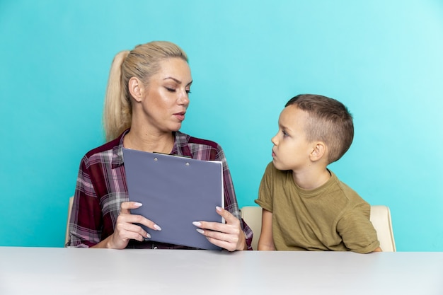 Mother helping her son with homework over pink