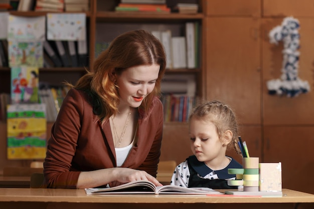 Mother helping kid after school preschooler doing homework with help of tutor home teaching concept