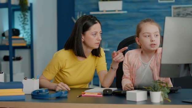 Mother helping young pupil with online classes on computer