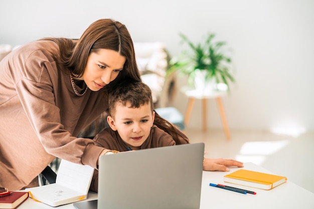 Mother helps her little son with online homework