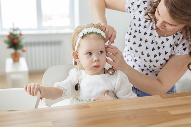 Mother helps to put on cochlear implant for her deaf little daughter hearing aid and deafness