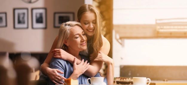 Mother and her adult daughter spending time together in cafe Banner design