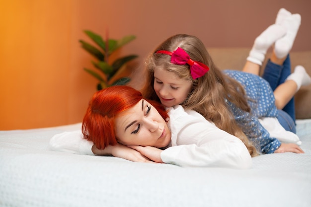 Mother and her baby daughter girl on bed in bedroom.