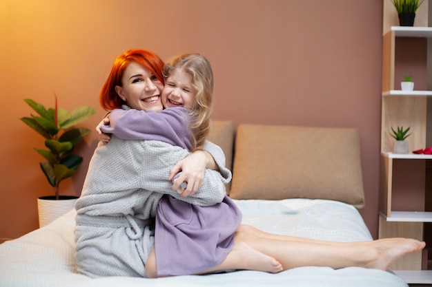 Mother and her baby daughter girl on bed in bedroom