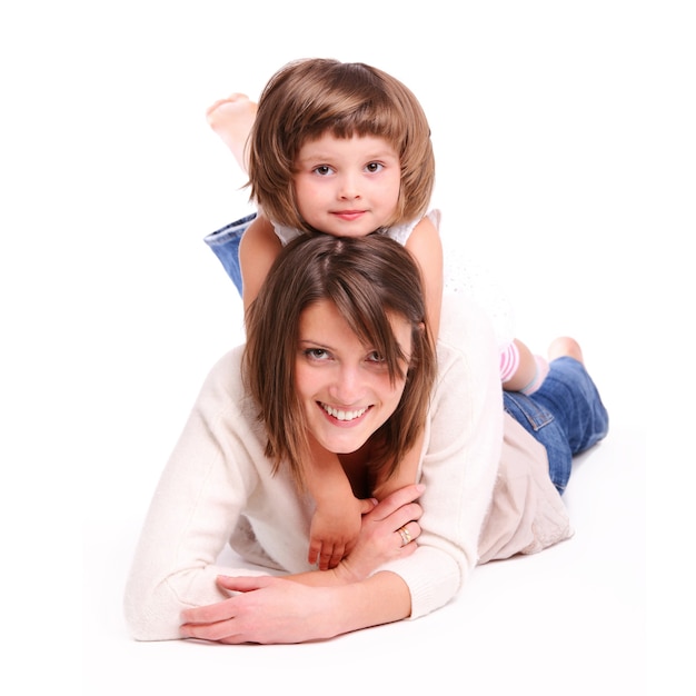 a mother and her baby girl lying on the floor and smiling over white background