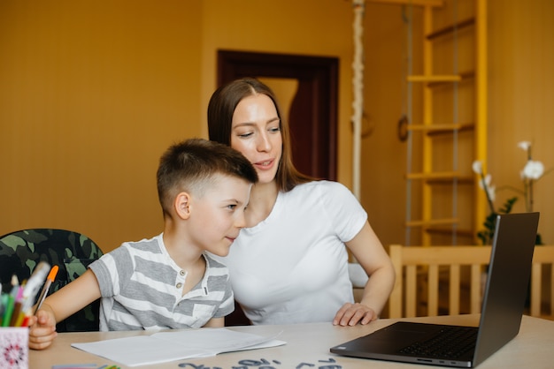 Una madre e suo figlio sono impegnati nell'apprendimento a distanza a casa davanti al computer. resta a casa, allenandoti.