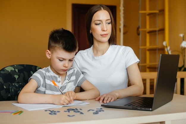 A mother and her child are engaged in distance learning at home in front of the computer