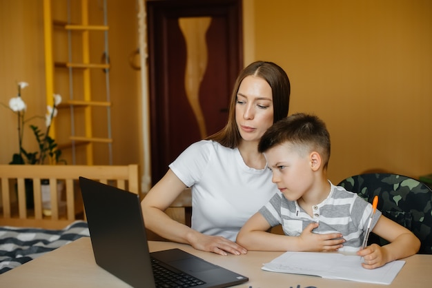 A mother and her child are engaged in distance learning at home in front of the computer