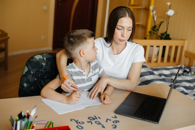 Una madre e suo figlio sono impegnati nell'apprendimento a distanza a casa davanti al computer.