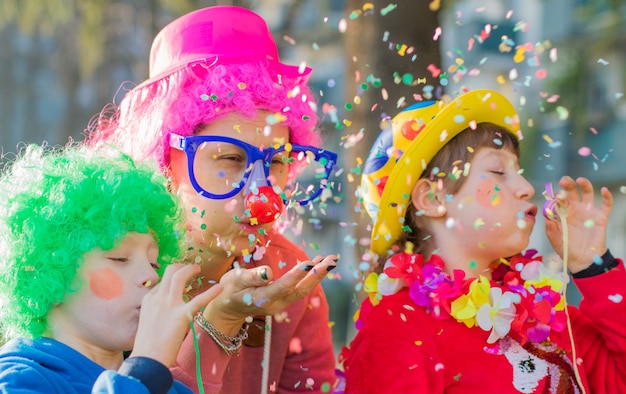 A mother and her children are playing with confetti in carnival costume