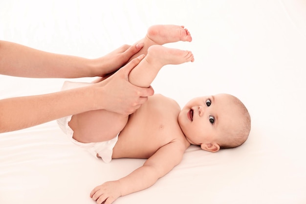 Mother and her cute child on white bed Baby massage and exercises