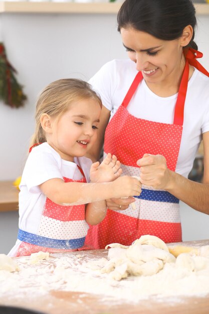 Mother and her cute daughter prepares the dough at wooden table Homemade pastry for bread or pizza Bakery background