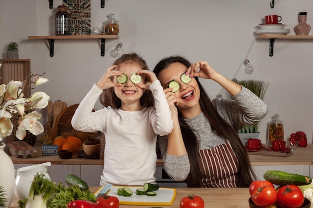 Mother and her daughter are making a vegetable salad and having fun at the kitchen
