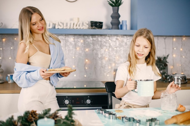 Mother and her daughter cooking Christmas ginger biscuits at the kitchen