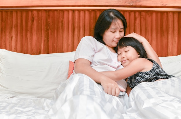 mother and her daughter hugging while sleeping 