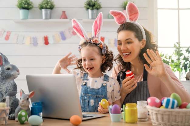 Mother and her daughter painting eggs Happy family preparing for Easter