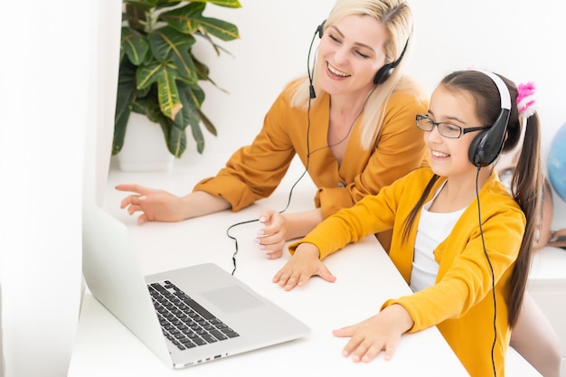 Mother and her girl listening to music on laptop. They sitting in living room. Natural light ambient.