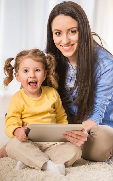 母と彼女の小さな娘は、タブレットを見ています。