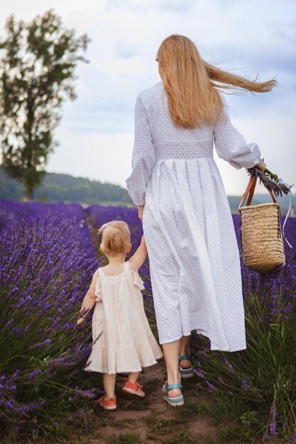 a mother and her little daughter are walking in a lavender field