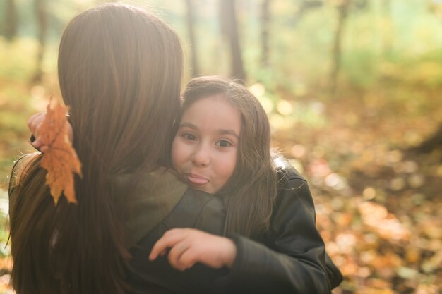 Mother and her little daughter in autumn park in fall season.