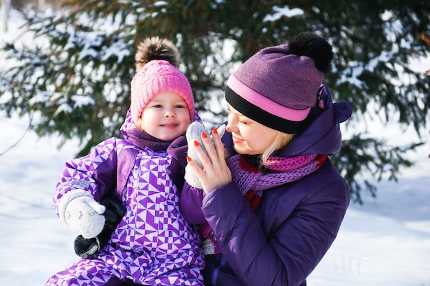 母と彼女の小さな娘が屋外で美しい冬の日を楽しんでいます。