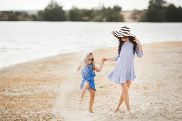 Madre e figlia piccola divertirsi sulla costa. giovane bella mamma e suo figlio che giocano vicino all'acqua