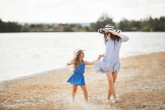 Madre e figlia piccola divertirsi sulla costa. giovane bella mamma e suo figlio che giocano vicino all'acqua