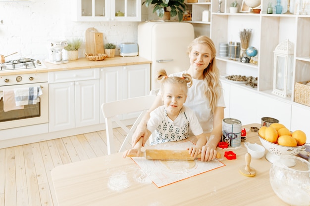 Photo a mother and her little daughter prepare baking dough together in their kitchen at home.