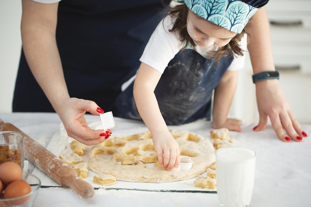 Mother and her little daughter preparing pastry in the kitchen