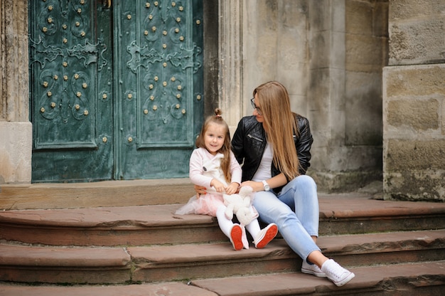 Mother and her little daughter sitting on the stairs