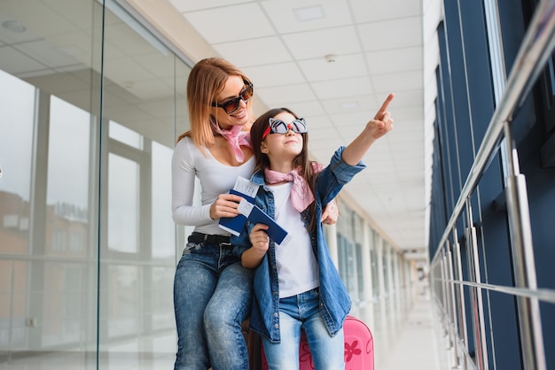 Mother and her little daughter with luggage at the airport