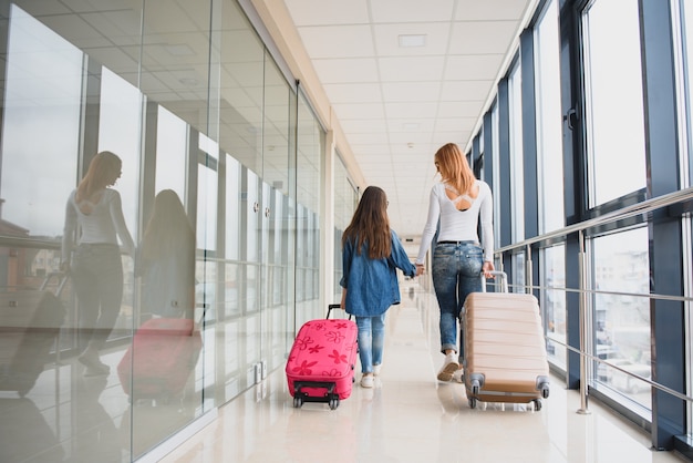 Mother and her little daughter with luggage at the airport