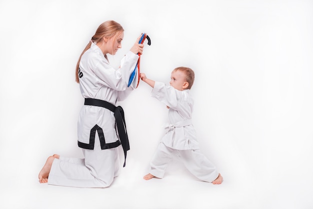 Mother her little son practicing martial arts on white