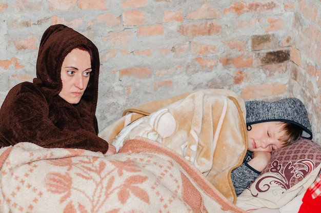 A mother and her son are hiding in the basement during an air raid