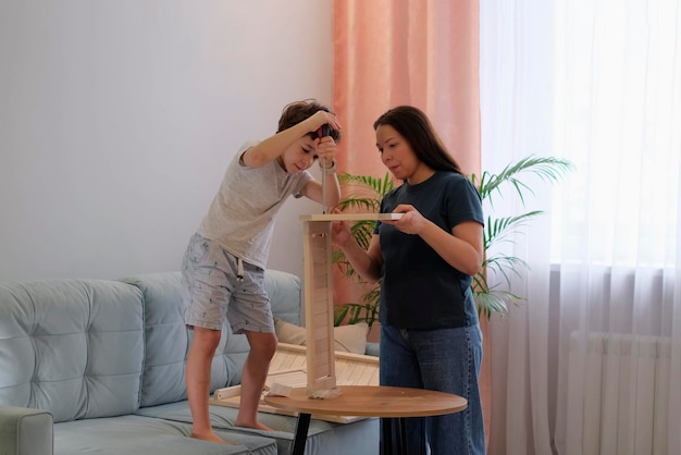 母と息子が家で一緒に家具を組み立てる