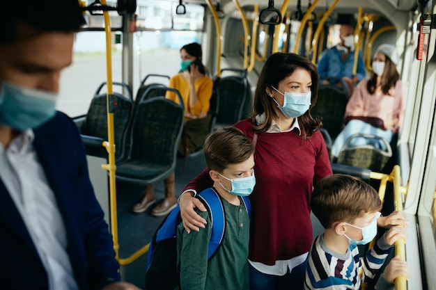 La madre e i suoi figli indossano maschere protettive mentre si spostano in autobus