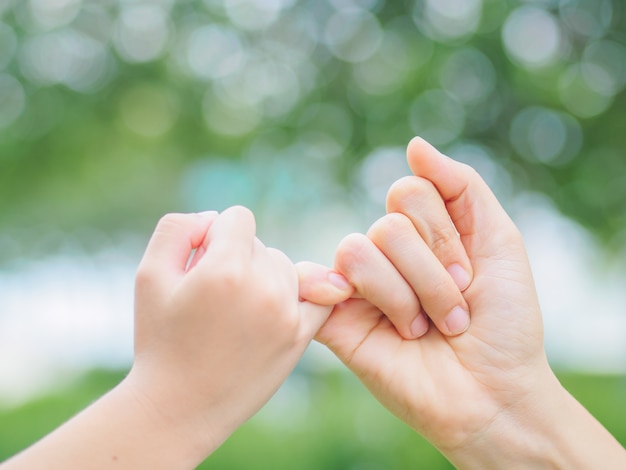 写真 屋外で春の日に彼女の子供の手を保持している母親。