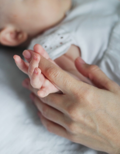 Mother holding baby feet, there is concept or idea of love, family and happiness at the home, like mother caring for newborn