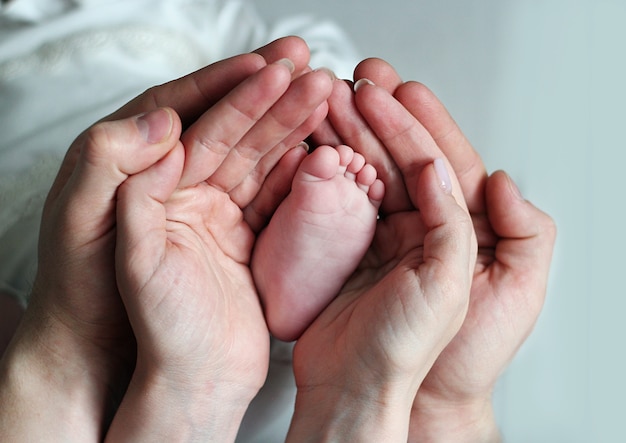 Mother holding baby feet, there is concept or idea of love, family and happiness at the home, like mother caring for newborn