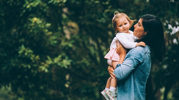 Photo mother holding baby at park