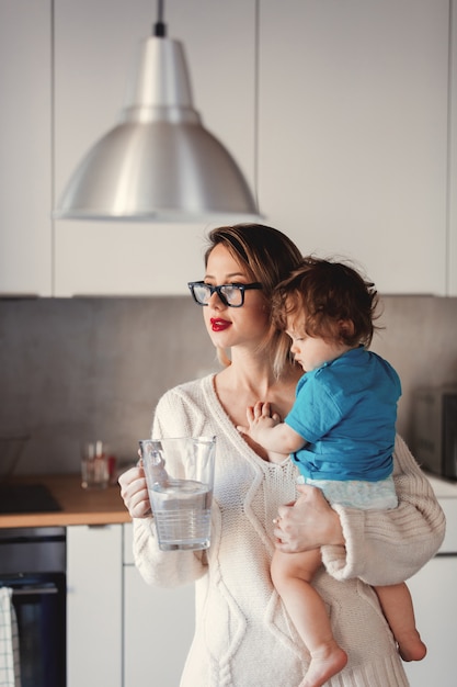 Foto madre che tiene un bambino e una caraffa d'acqua