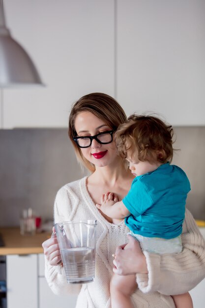 子供が水とデカンタを保持している母親